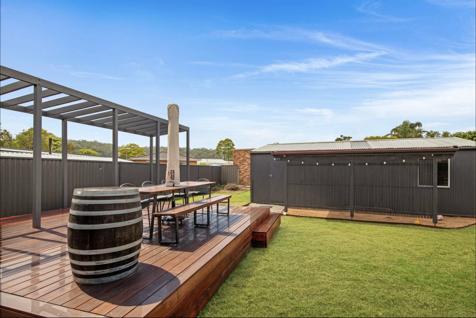 The timber deck and lawn at Sea Salt at Maloney's, with a long outdoor table under a pergola