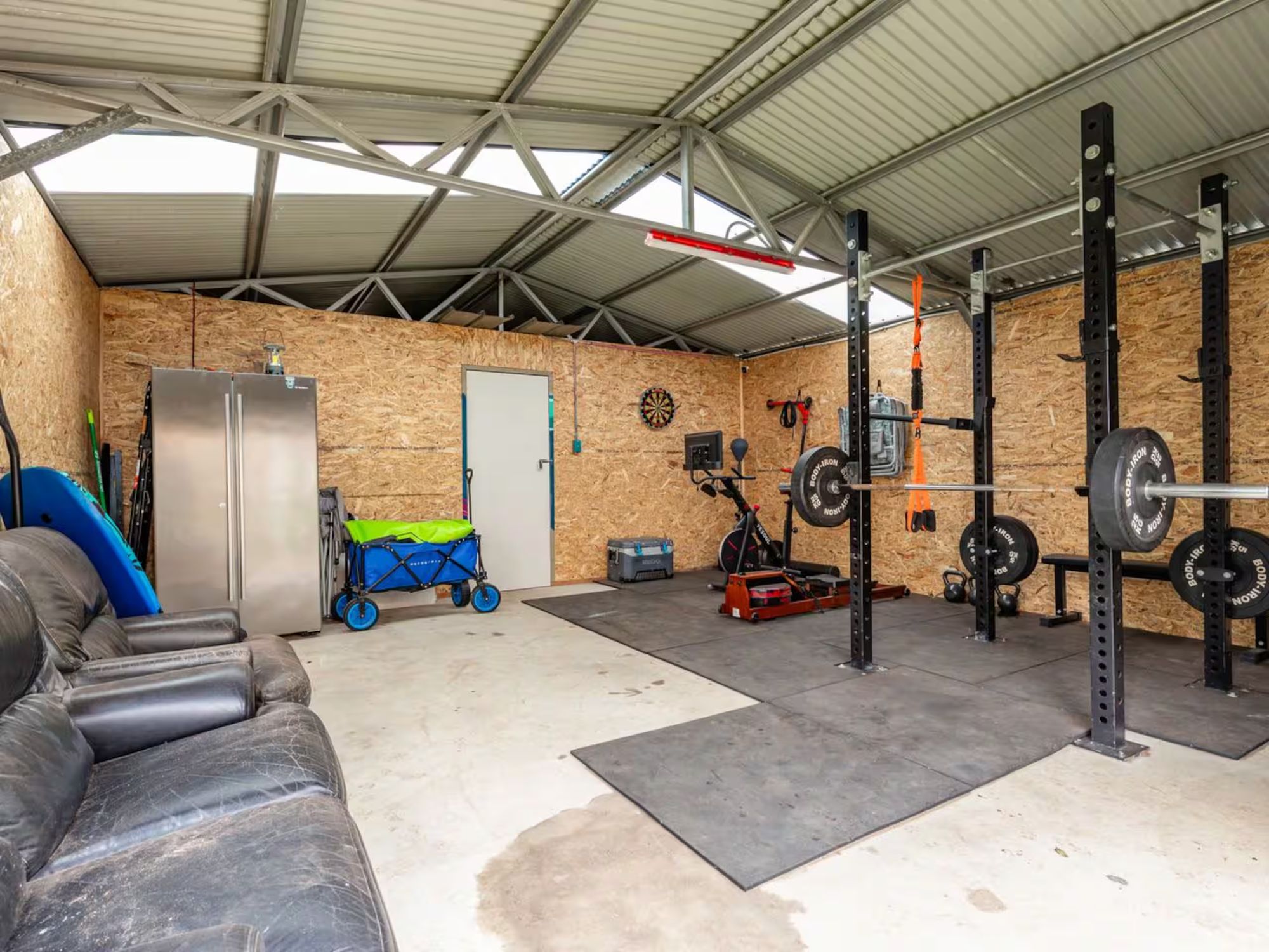 The gym in the garage, with a squat rack, barbell and bench